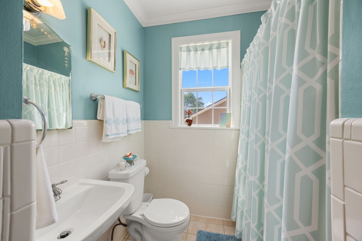 801 West Main Street Brenham, TX 77833 - Photo 32 of 50 The upstairs guest bath is bright and inviting with cheerful finishes, a shower and tub combination, and a window that fills the space with natural light. White tile accents add to the space.