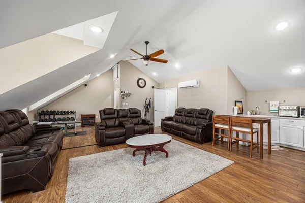 a living room with furniture kitchen view and a wooden floor