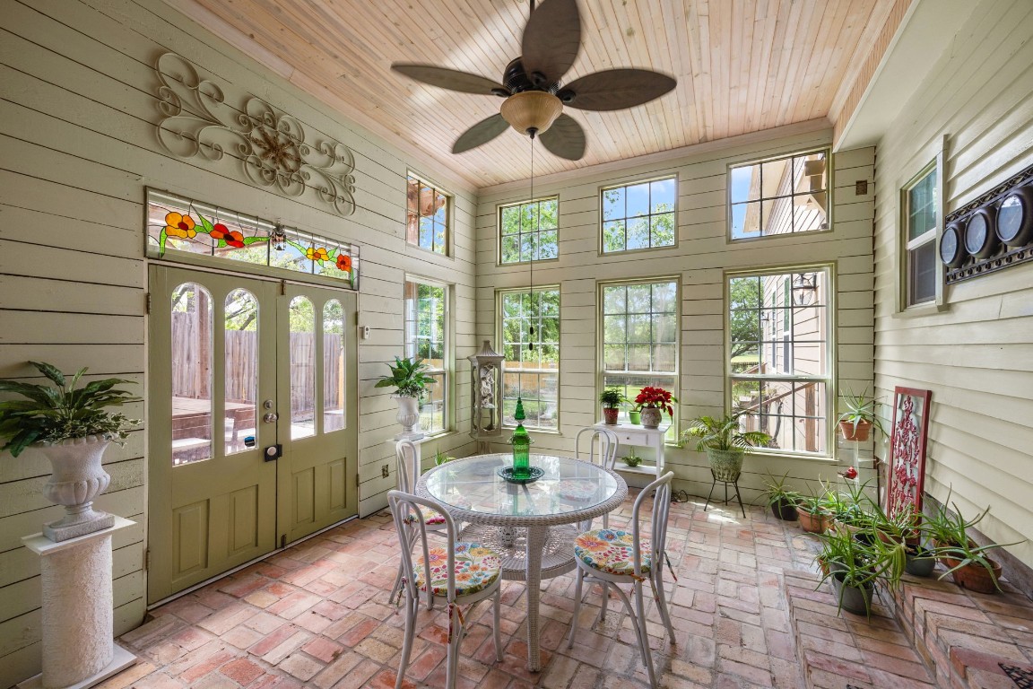 801 West Main Street Brenham, TX 77833 - Photo 40 of 50 Enjoy year round relaxation in the stunning sunroom featuring soaring wood plank ceilings, walls of windows that flood the space with natural light, brick flooring, and direct access to the backyard deck.