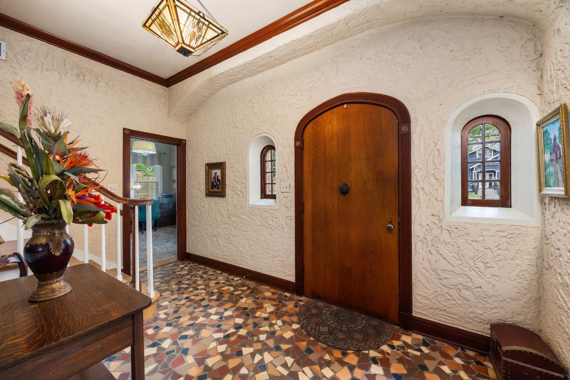 801 West Main Street Brenham, TX 77833 - Photo 4 of 50 Step inside to discover a welcoming foyer filled with historic character, featuring terrazzo flooring, stained wood trim, and an arched front door flanked by charming inset windows. Textured walls and period details create a warm and inviting introduction to the home.
