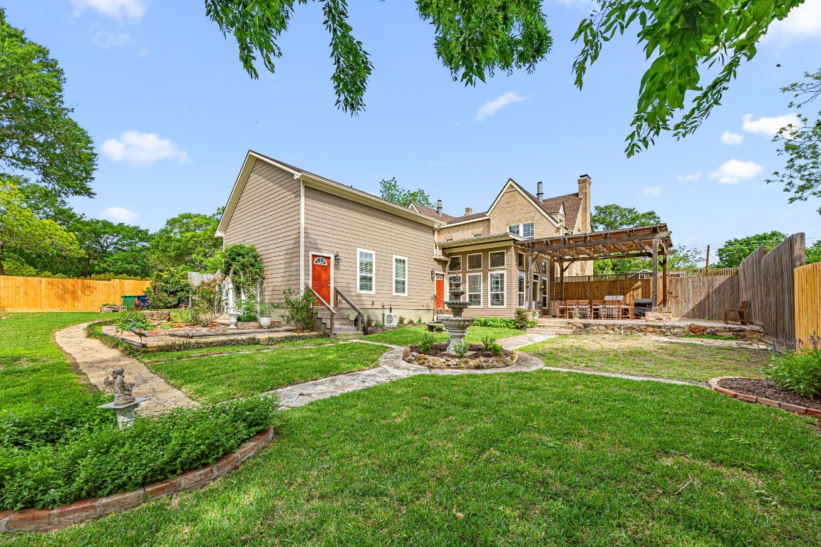 801 West Main Street Brenham, TX 77833 - Photo 48 of 50 Meticulously maintained landscaping surrounds the backyard with winding stone walkways, manicured flower beds, and a charming fountain that creates a peaceful garden like setting.