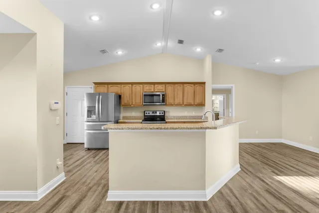 a large kitchen with stainless steel appliances a large counter top a stove and a refrigerator