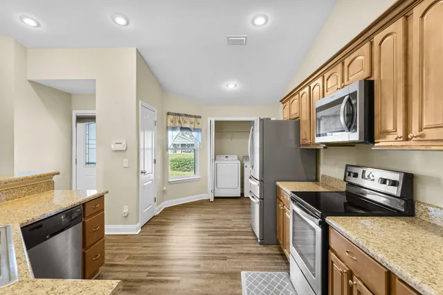 a kitchen with stainless steel appliances granite countertop a refrigerator a stove top oven a sink and dishwasher