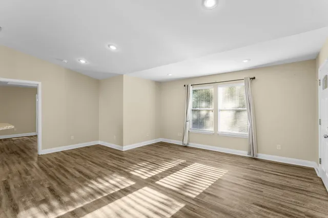a view of an empty room with wooden floor and a window