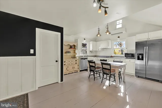 a kitchen with stainless steel appliances kitchen island granite countertop a refrigerator a stove a sink a dining table and chairs