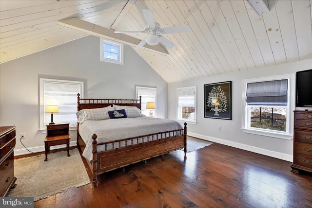 a bedroom with a large bed wooden floor and windows