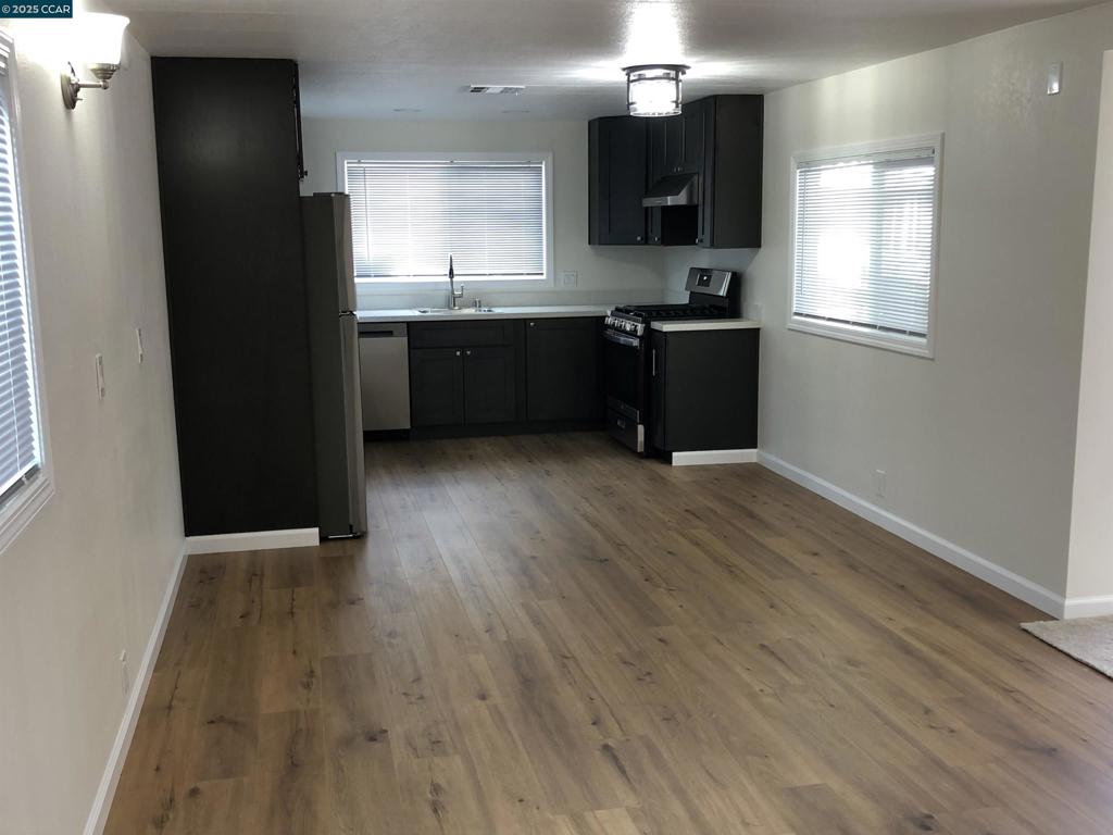 4556 Appian Way El Sobrante, CA 94803 - Photo 16 of 16 an empty room with wooden floor and kitchen