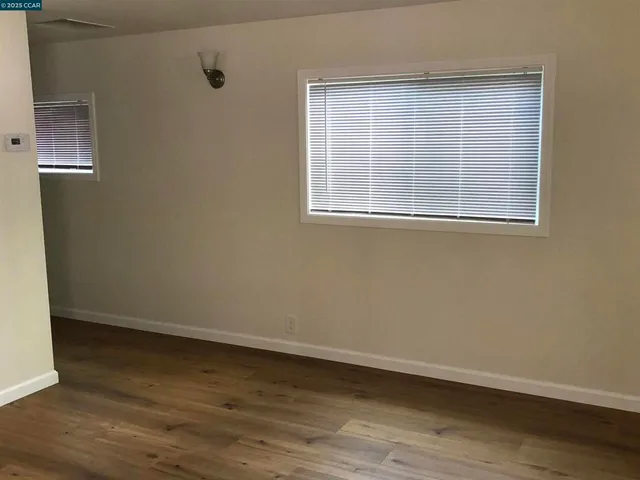 an empty room with wooden floor and kitchen