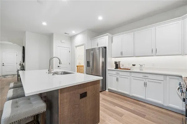 a kitchen with stainless steel appliances granite countertop a table chairs sink refrigerator and cabinets