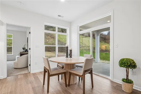 a kitchen with a dining table chairs wooden floor appliances and cabinets