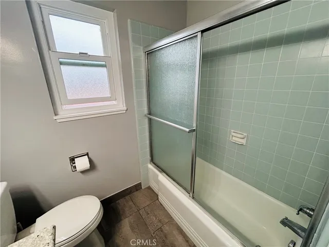 a bathroom with a granite countertop bathtub shower and toilet