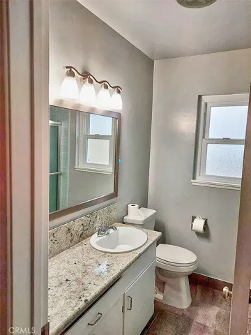 a bathroom with a granite countertop toilet sink and mirror