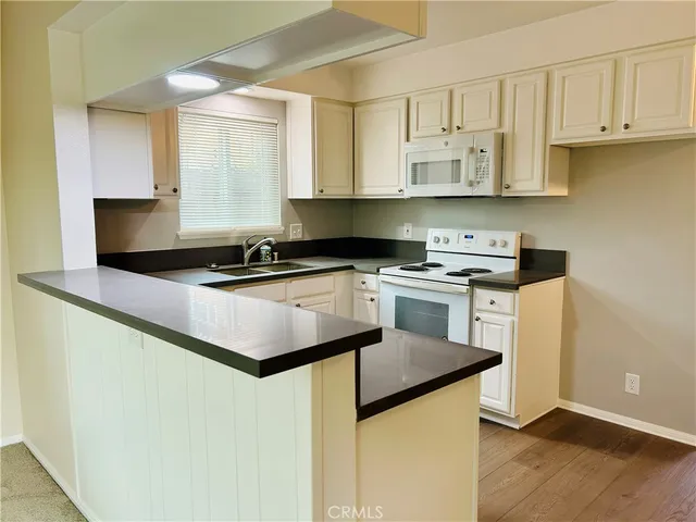 a kitchen with granite countertop a sink a stove and cabinets