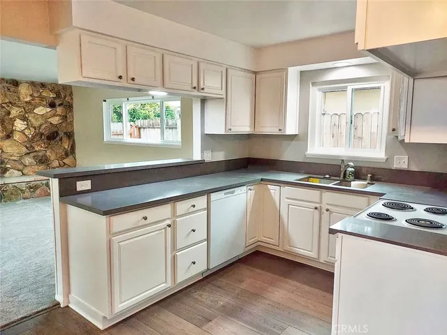 a kitchen with granite countertop white cabinets and white appliances