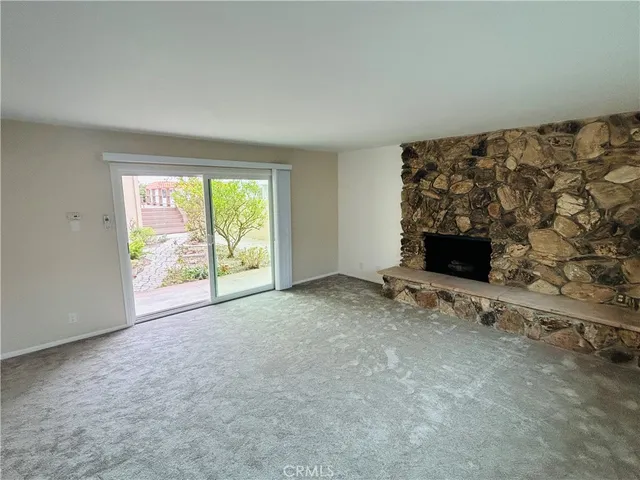 a view of an empty room with a fireplace and a window