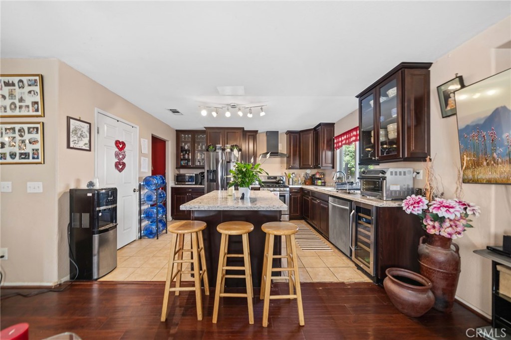4475 Willowglen Way Hemet, CA 92545 - Photo 17 of 33 a kitchen with stainless steel appliances kitchen island granite countertop a refrigerator a stove top oven and a dining table with wooden floor