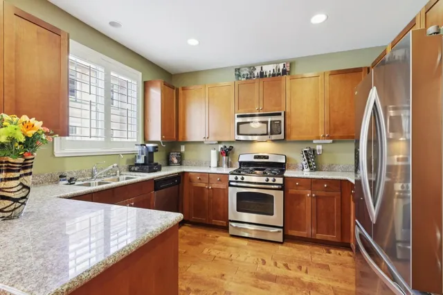 a kitchen with stainless steel appliances granite countertop a refrigerator a sink a stove a washer dryer and a refrigerator