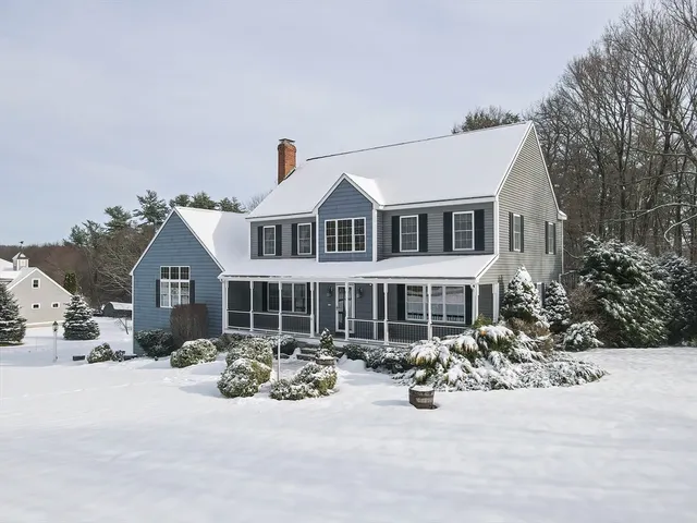 a view of a white house and a large tree in front of it