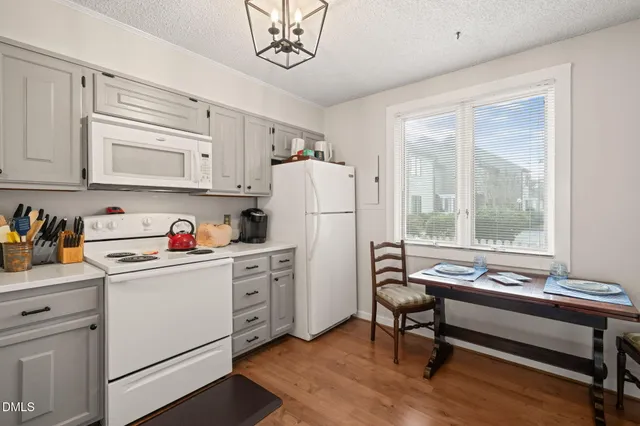 a kitchen with a refrigerator a stove cabinets and a dining table