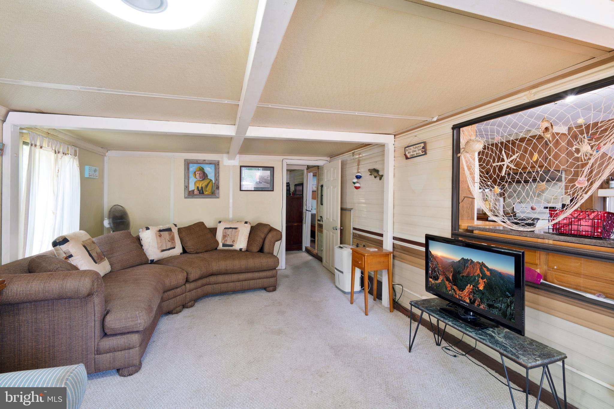 111 Beach Harbor Road, Unit 11F Grasonville, MD 21638 - Photo 3 of 13 a living room with furniture a flat screen tv and a wall painting