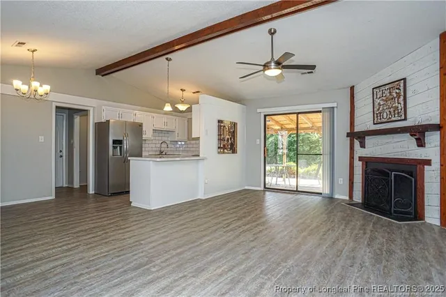 a view of a kitchen with a ceiling fan a kitchen view and a fireplace