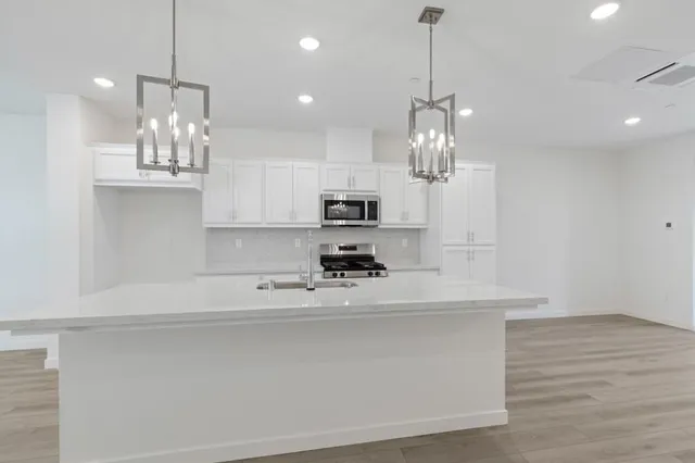 a view of a kitchen with kitchen island a sink stainless steel appliances and cabinets