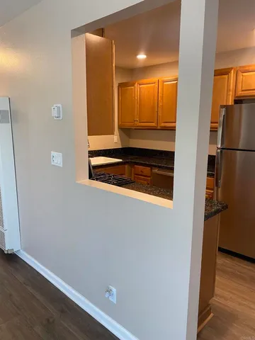 a kitchen with kitchen island granite countertop wooden floors stainless steel appliances and a sink