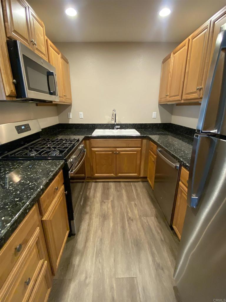 2088 Montgomery Avenue, Unit M Cardiff-by-the-Sea, CA 92007 - Photo 21 of 43 a kitchen with stainless steel appliances granite countertop a sink a stove microwave and cabinets