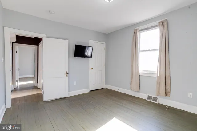 a view of an empty room with wooden floor and closet