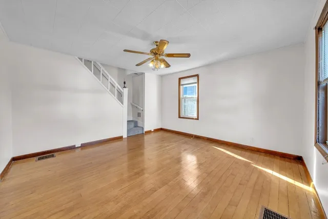 a view of empty room with wooden floor and fan
