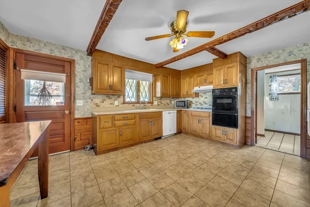 a kitchen with kitchen island granite countertop a sink appliances cabinets and furniture