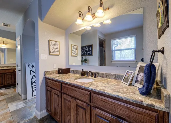 a bathroom with a granite countertop sink a mirror and a shower