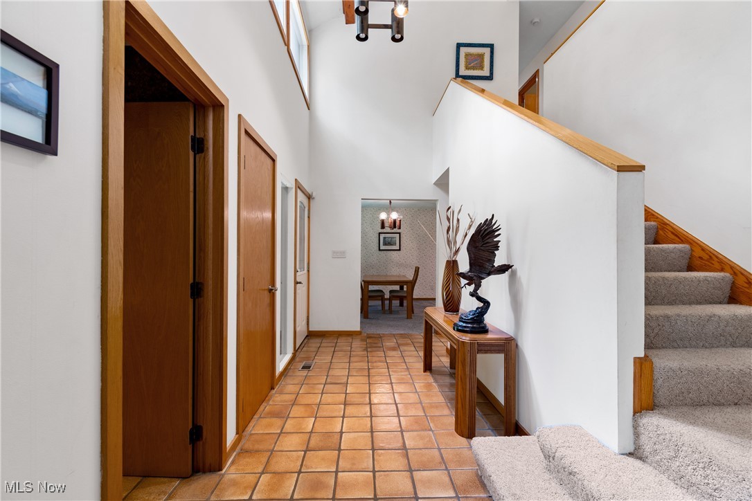 7098 Taylor Road Clinton, OH 44216 - Photo 7 of 39 Hallway featuring a towering ceiling, a chandelier, and light tile patterned floors