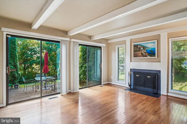 a view of a livingroom with furniture wooden floor fireplace and windows