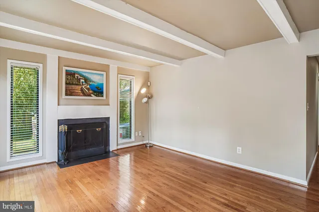 a view of an empty room with wooden floor fireplace and a window