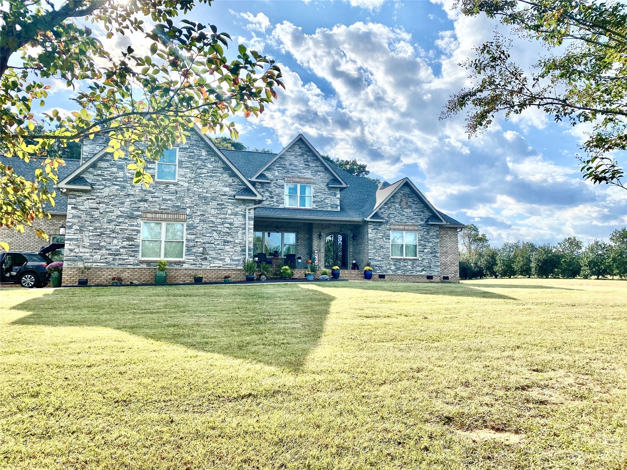 a front view of a house with a garden and trees