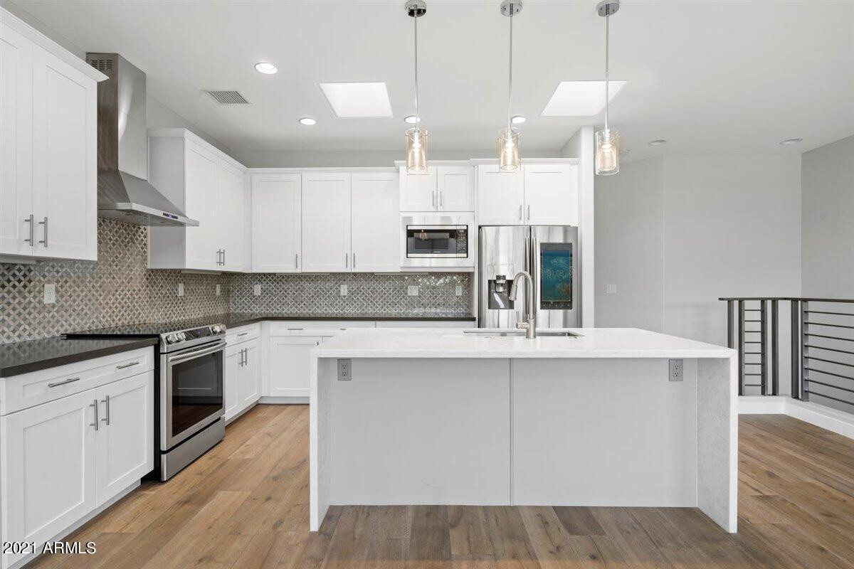 a kitchen with kitchen island a stove a sink a center island and wooden floor