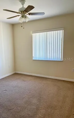 an empty room with a window and a fan
