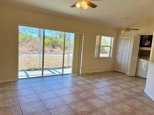 a view of an empty room with window and chandelier fan