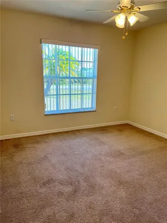 an empty room with a chandelier fan and windows