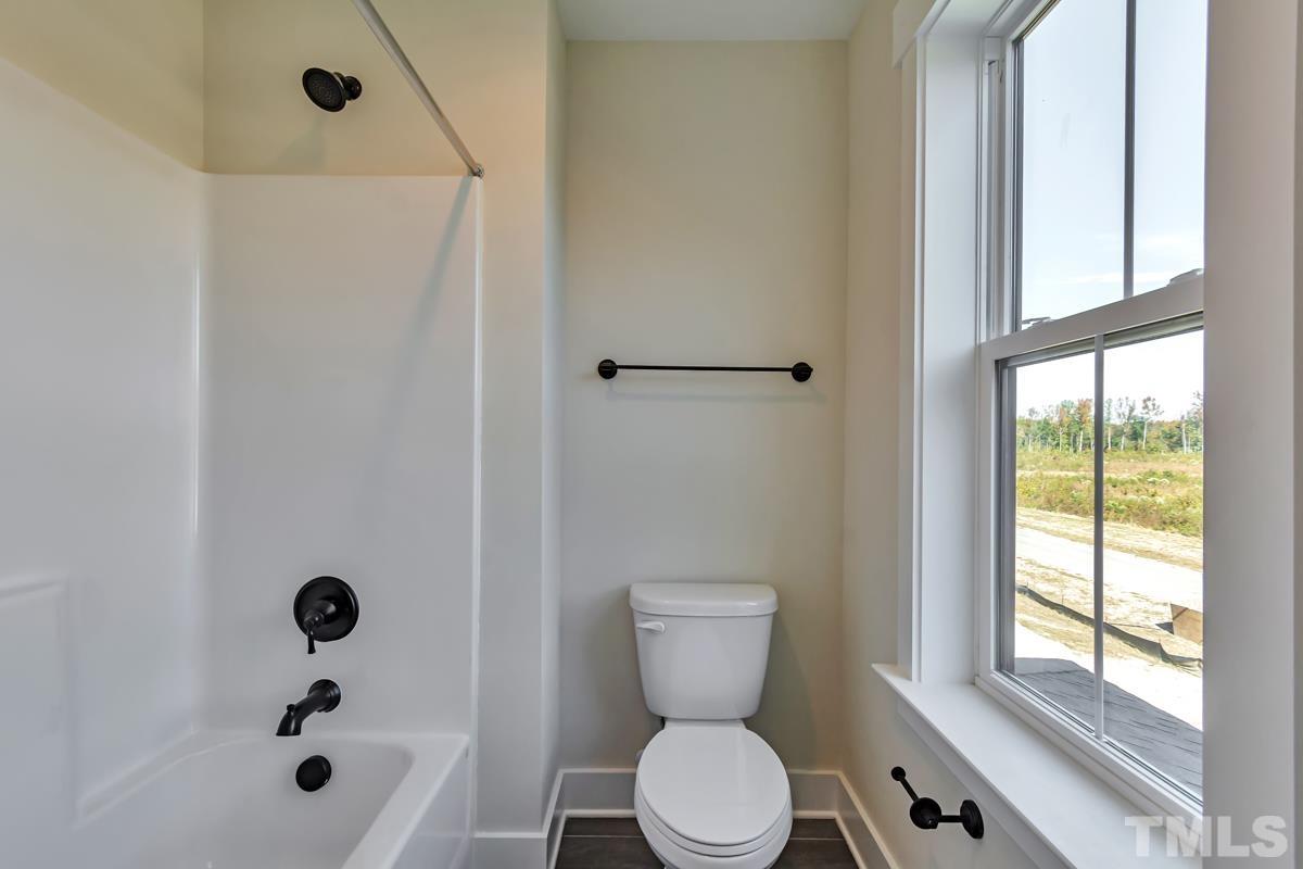 6409 Camellia Creek Drive Raleigh, NC 27603 - Photo 24 of 30 a bathroom with a toilet a window and tub