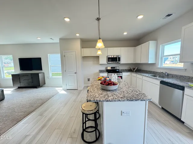 a kitchen with kitchen island granite countertop a sink stove and refrigerator