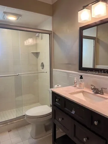 a bathroom with a toilet a sink a glass door a shower and a mirror