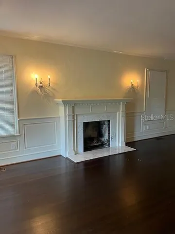 an empty room with wooden floor fireplace and windows