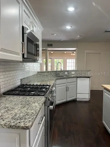 a kitchen with stainless steel appliances granite countertop a stove a sink and a microwave