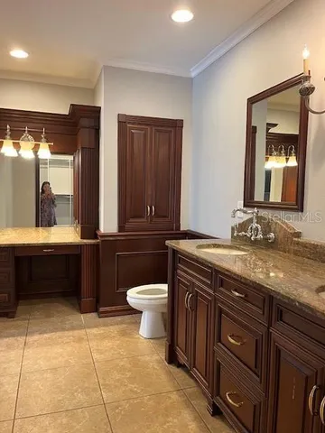 a bathroom with a granite countertop toilet sink and mirror