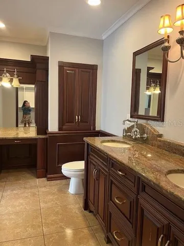 a bathroom with a granite countertop sink a toilet and a mirror