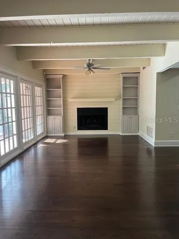 a view of wooden floor fire place and windows in an empty room