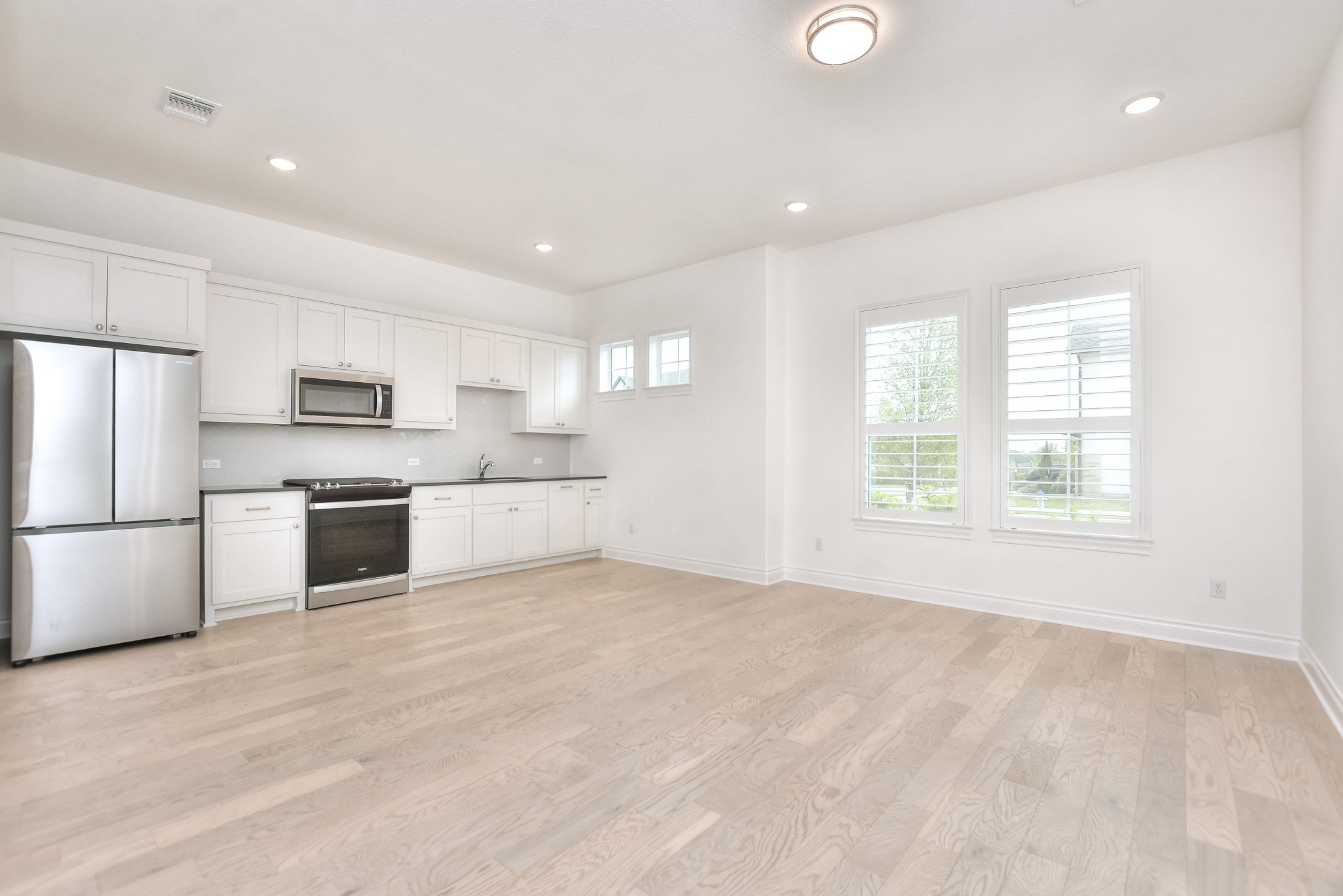 309 Wolf Rdg Road Georgetown, TX 78628 - Photo 21 of 39 Kitchen featuring stainless steel appliances, white cabinets, dark countertops, light wood-type flooring, and recessed lighting