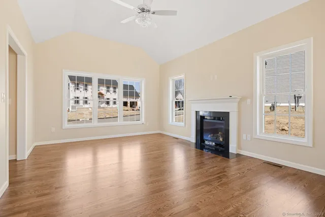 an empty room with windows fireplace and wooden floor
